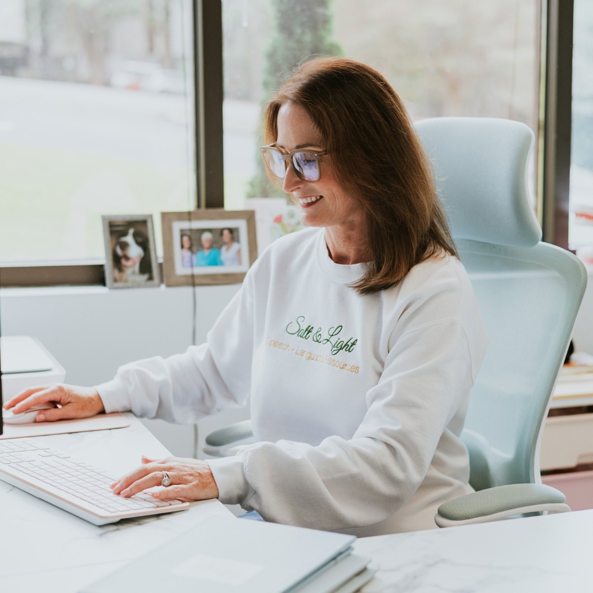 Amanda Mavrakos sitting at her desk, smiling as she works at a computer